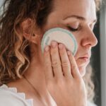 Image of woman using an organic stories face pad to remove make up from her face.