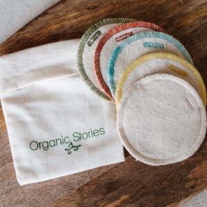 Image of small cotton pouch and 5 round reusable face pads alongside with a wooden board background.