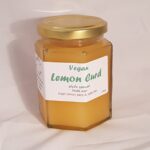 Image of jar of lemon curd with gold lid and white label. Jar has pleasing hexagonal sides rather than rounded.