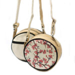 Image of front and bag of small round jute bag with cherry blossom on the front and long strap