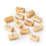 Product Image showing a range of vegan nail brushes with wooden handles, different designs are engraved at the top including a fox, a lion, a swan and others