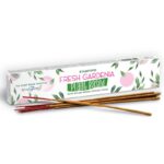 Attractive white box with small green leaves and pink gardenia pattern containing plant based incense sticks, some of the incense sticks are in front of the box on display.